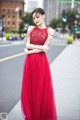 A woman in a red dress standing on a city street.