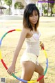 A woman in a white bikini holding a hula hoop.