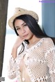 A woman in a white crochet top and a straw hat.