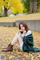 A woman sitting on the ground covered in leaves.