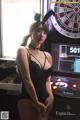 A woman in a black lingerie standing in front of a dart board.