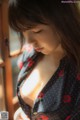 A woman in a polka dot shirt looking out a window.