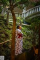 A woman in a kimono standing on a set of stairs.