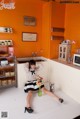 A woman sitting on the floor in a kitchen.