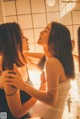 A couple of women standing next to each other in a bathroom.