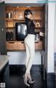 A woman standing in front of a cabinet in a room.