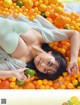 A woman laying on top of a pile of oranges.