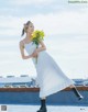 A woman in a white dress holding a bunch of yellow flowers.