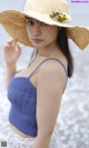 A woman wearing a straw hat on the beach.