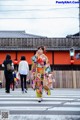 A woman in a colorful kimono walking across a crosswalk.