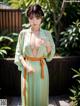 A woman in a green and orange kimono posing for a picture.