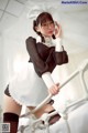 A woman in a maid outfit is posing on a bed.