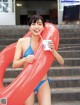 A woman in a blue bikini holding a cup of ice cream.