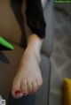 A woman's feet with red nail polish sitting on a couch.