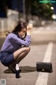 A woman sitting on the ground next to a bottle of beer.