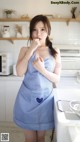 A woman in a blue apron standing in a kitchen.