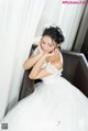 A woman in a wedding dress sitting on a couch.