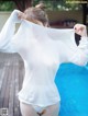 A woman in a white shirt is standing by a pool.