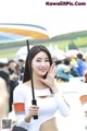 A woman holding an umbrella in front of a crowd.