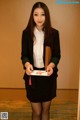 A woman in a black skirt and white shirt holding a book.