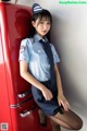 A woman in a police uniform leaning against a red refrigerator.