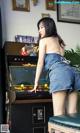 A woman in a denim skirt playing a video game.