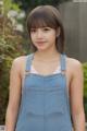 A young woman wearing a denim overalls poses for a picture.