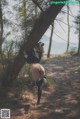 A woman leaning against a tree in the woods.