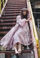 A woman in a pink dress sitting on a set of stairs.